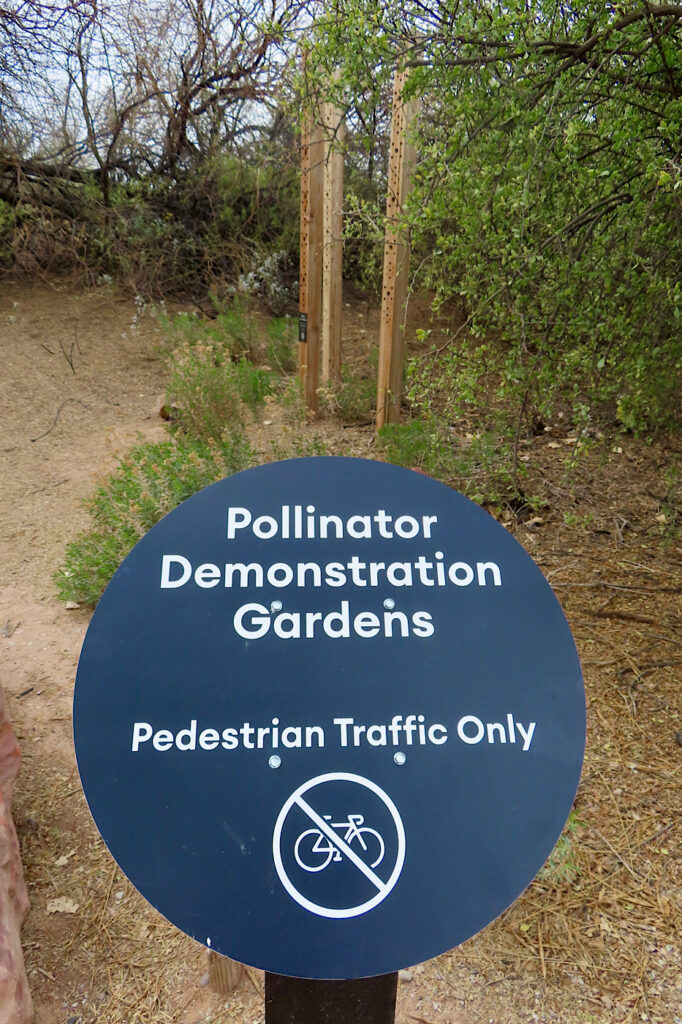 Round sign reading: Pollinator Demonstration Gardens, Pedestrian Traffic Only (and image of a bicycle with cross through it)