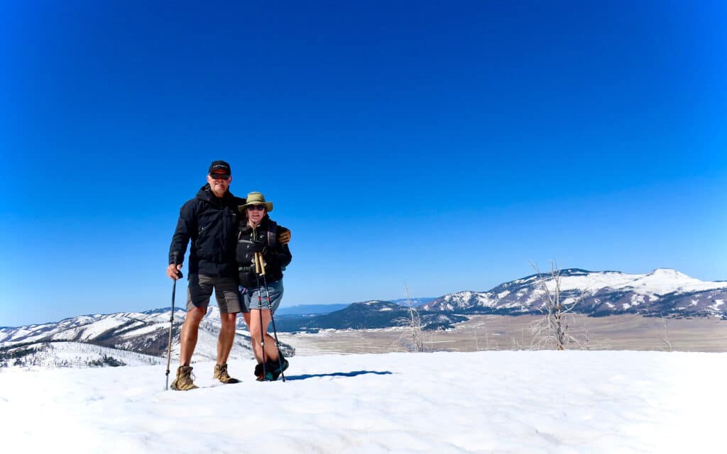 Man and woman hikers standing on snowy summit.