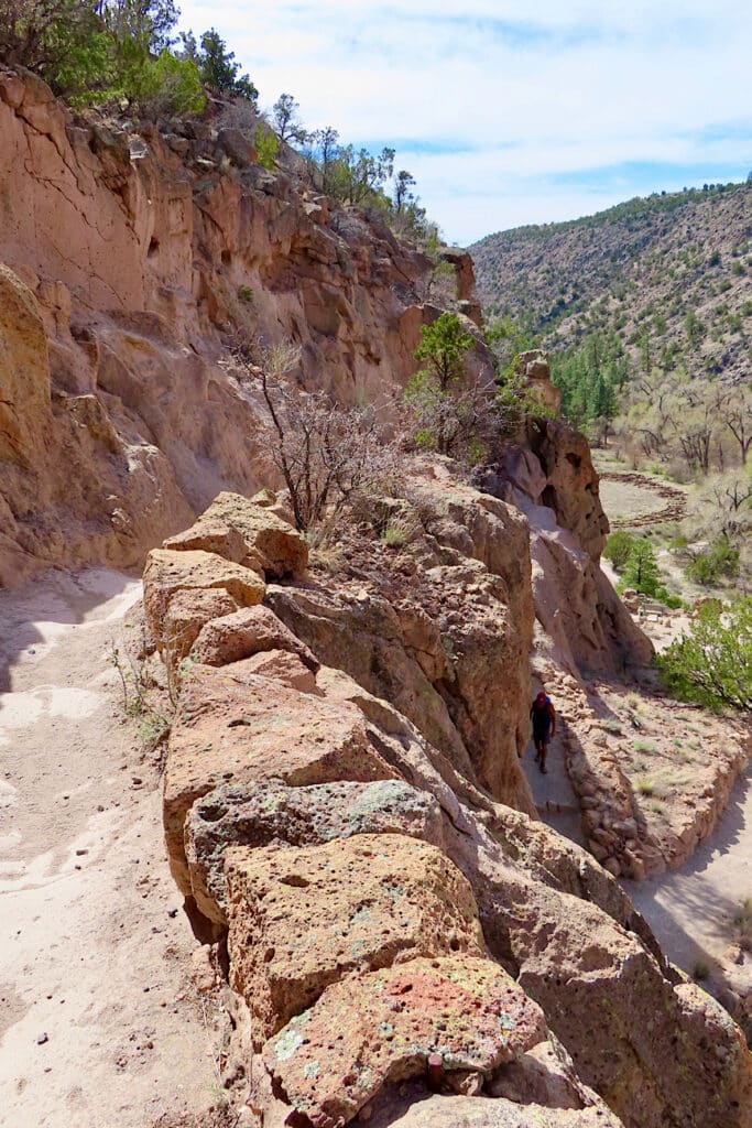 Rock-lined trail zigzagging down cliff towards valley below.