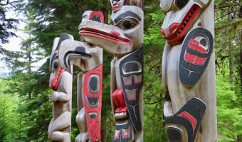 Four red and black painted totem poles