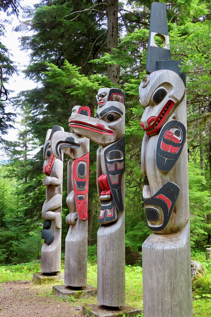 Four red and black painted totem poles