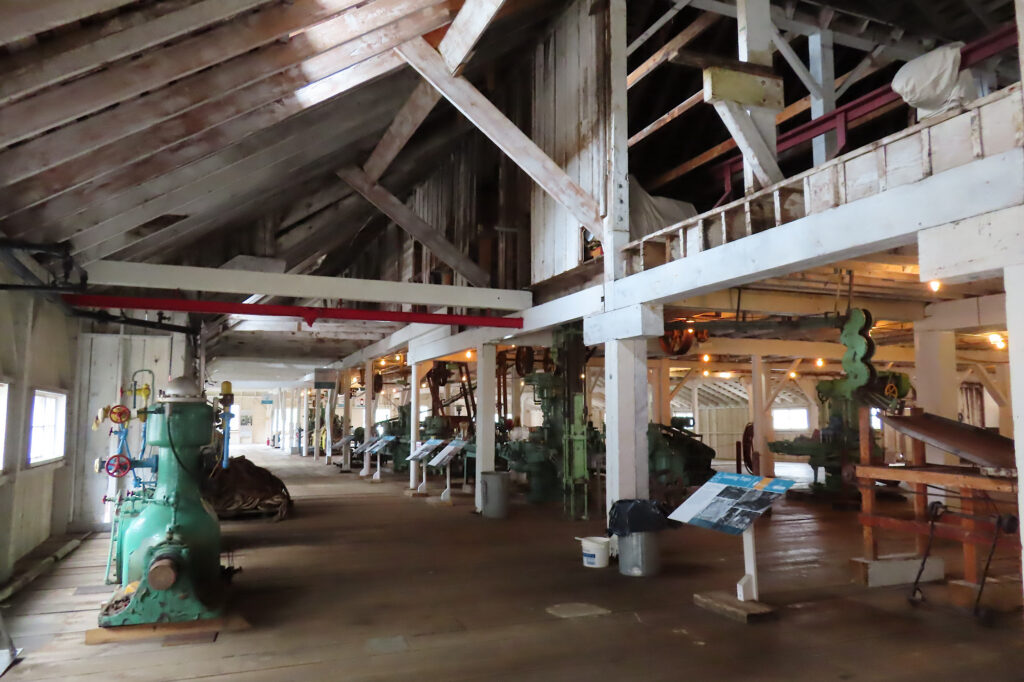 Interior of old wooden building with white washed walls and plank flooring.