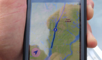 Man's hand holding cell phone with map on it.