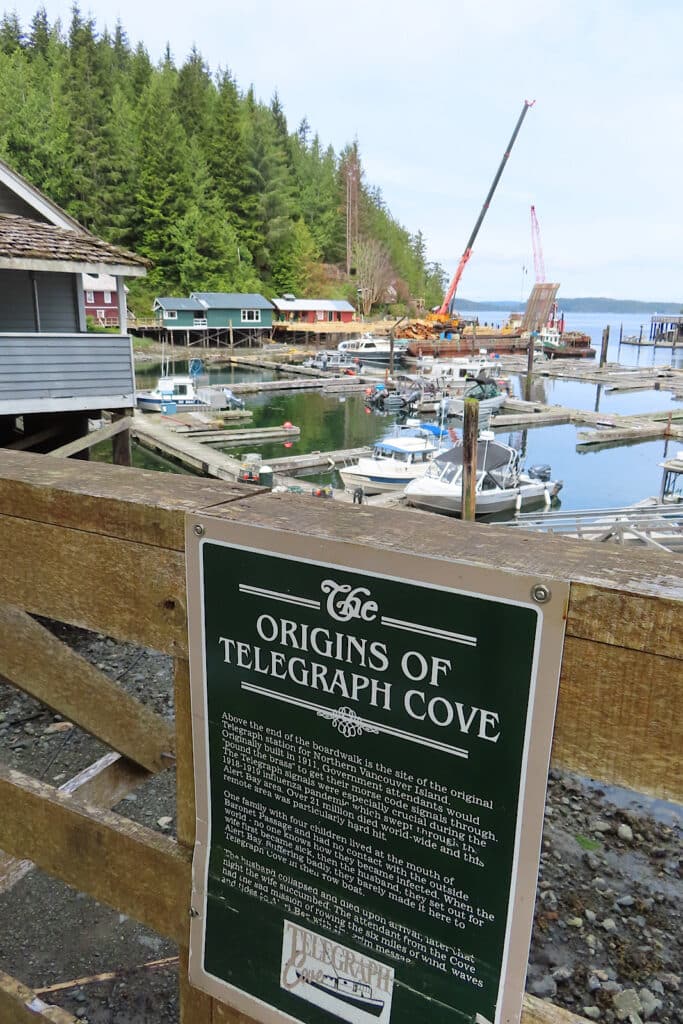 Interpretive sign on railing above cove reading: "Origins of Telegraph Cove" with text below.