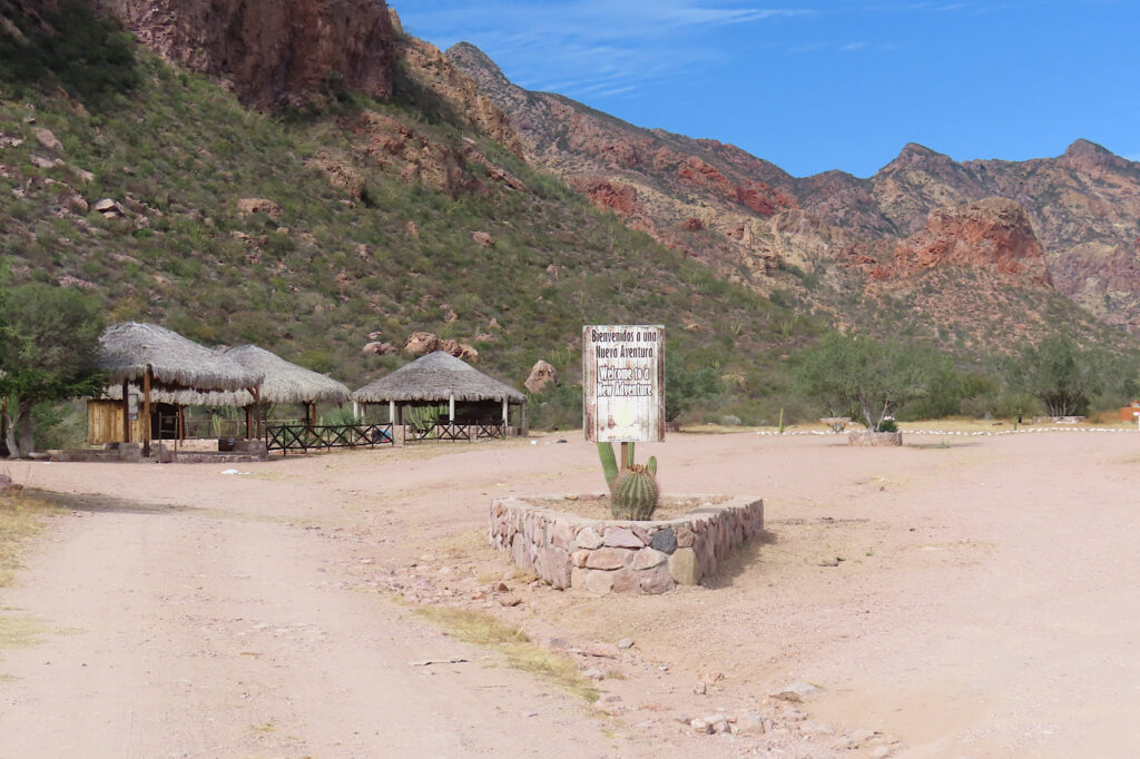 Entrance sign and parking lot with canyon behind.