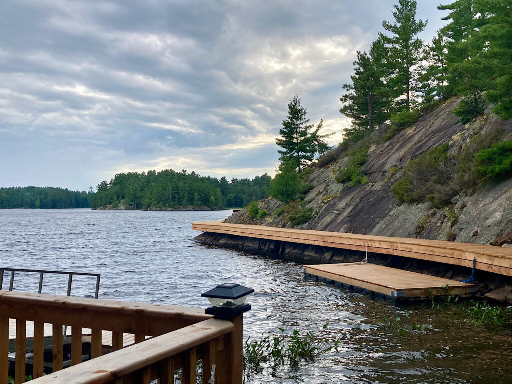 Series of dock and wooden boardwalk at tree-lined lake edge.