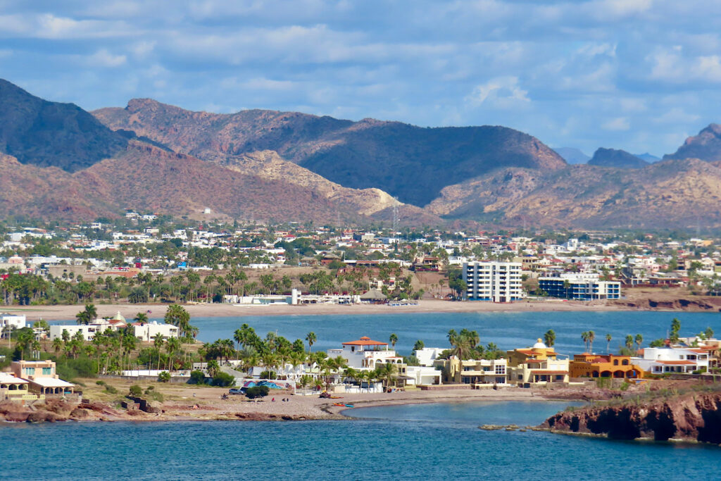 Coastal town with beach and ocean and distant mountains.