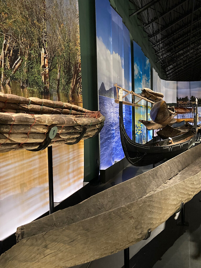 Image of two old wood canoes in a museum setting.