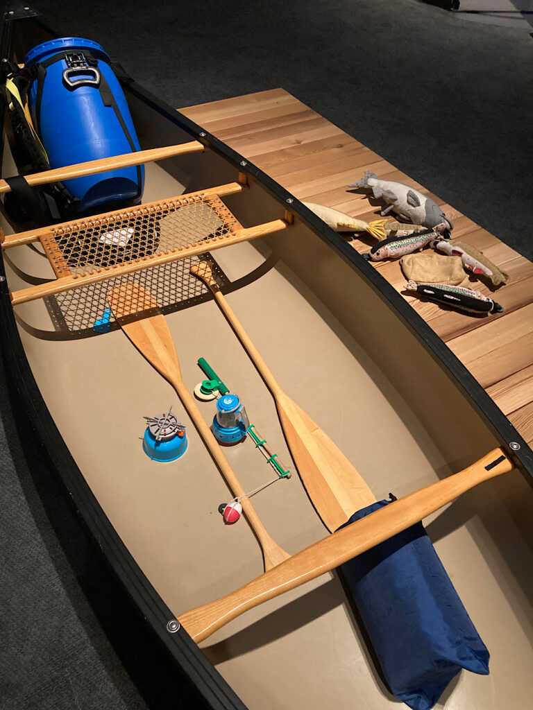 Boat wiht mini paddles, fishing rod and camping gear.