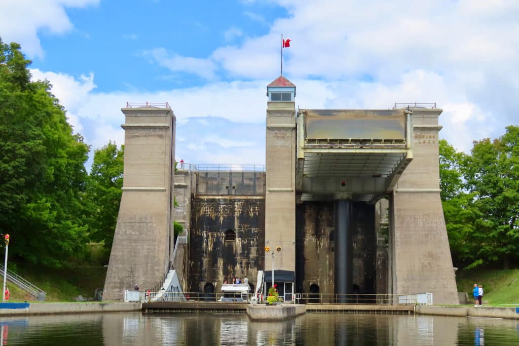 Large concrete structure above a waterway with trees on sides under blue sky.
