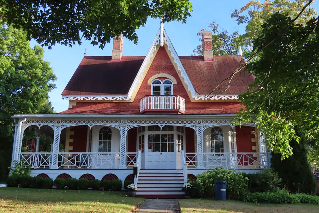 Image of an historic home painted brick red with white trim.
