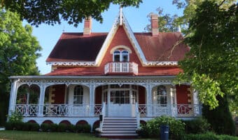 Image of an historic home painted brick red with white trim.