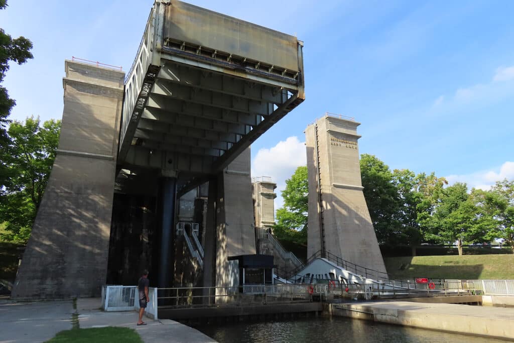 Large concrete structure with raised section above water under blue sky.