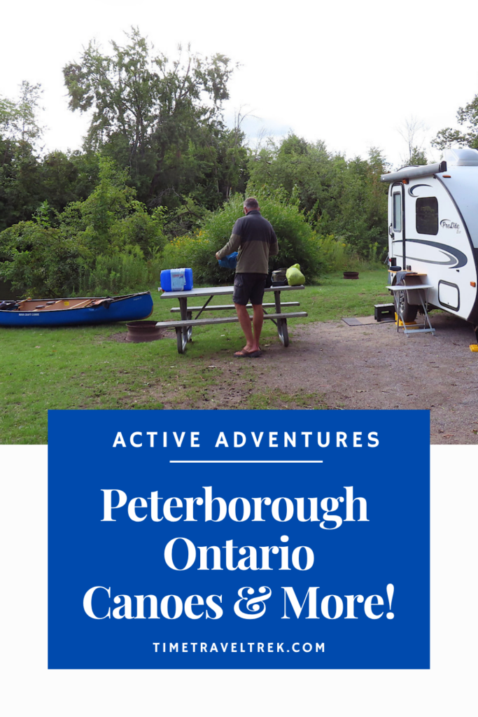 Pin image of man standing by small trailer with blue canoe at water's edge.Text in blue box reads: Active Adventures. Peterborough Ontario Canooes and More! TimeTravelTrek.com