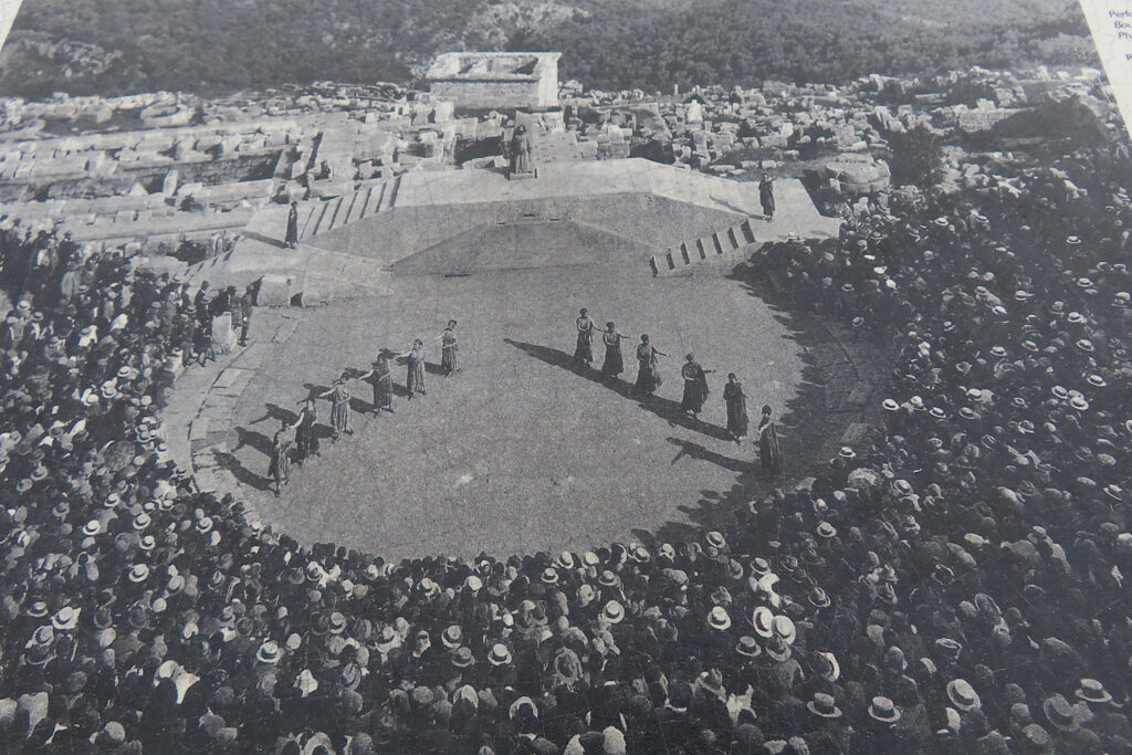 Black and white image of large theatre filled with an audience and actors in centre stage.