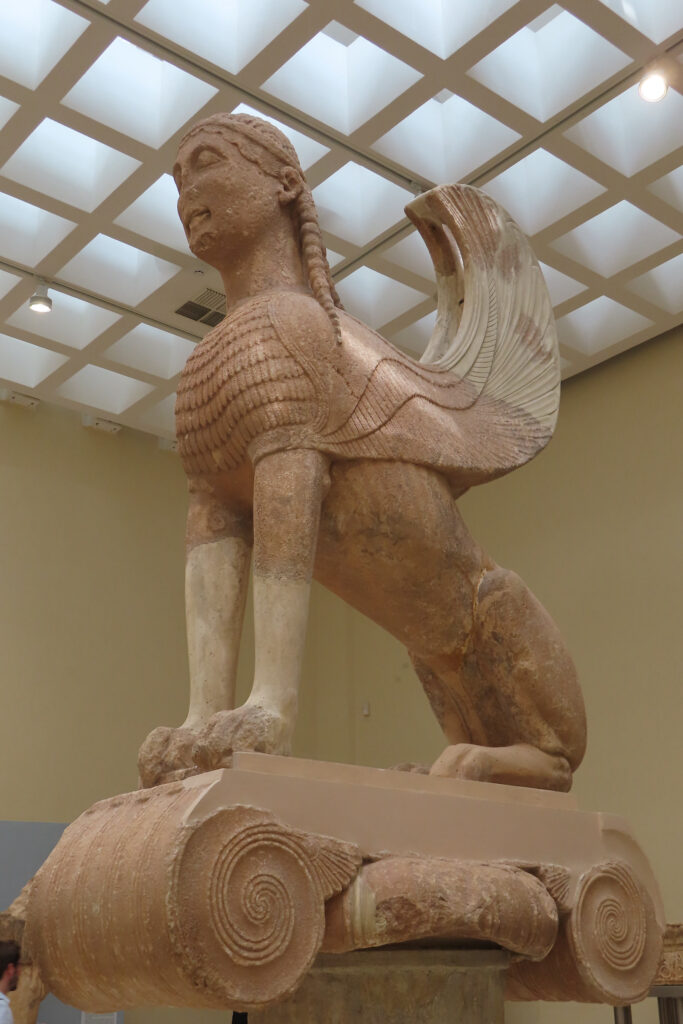 Image of a carved stone lion with head of persona and wings.