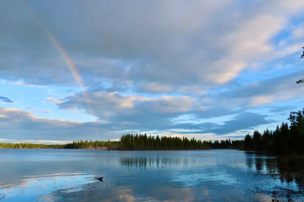 Rainbow in partially cloudy skies over lake