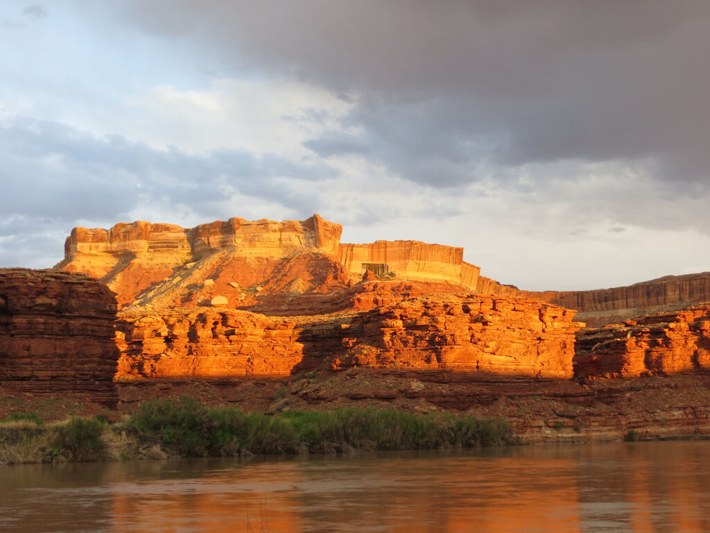 Sunset glow on cliffs above a river.