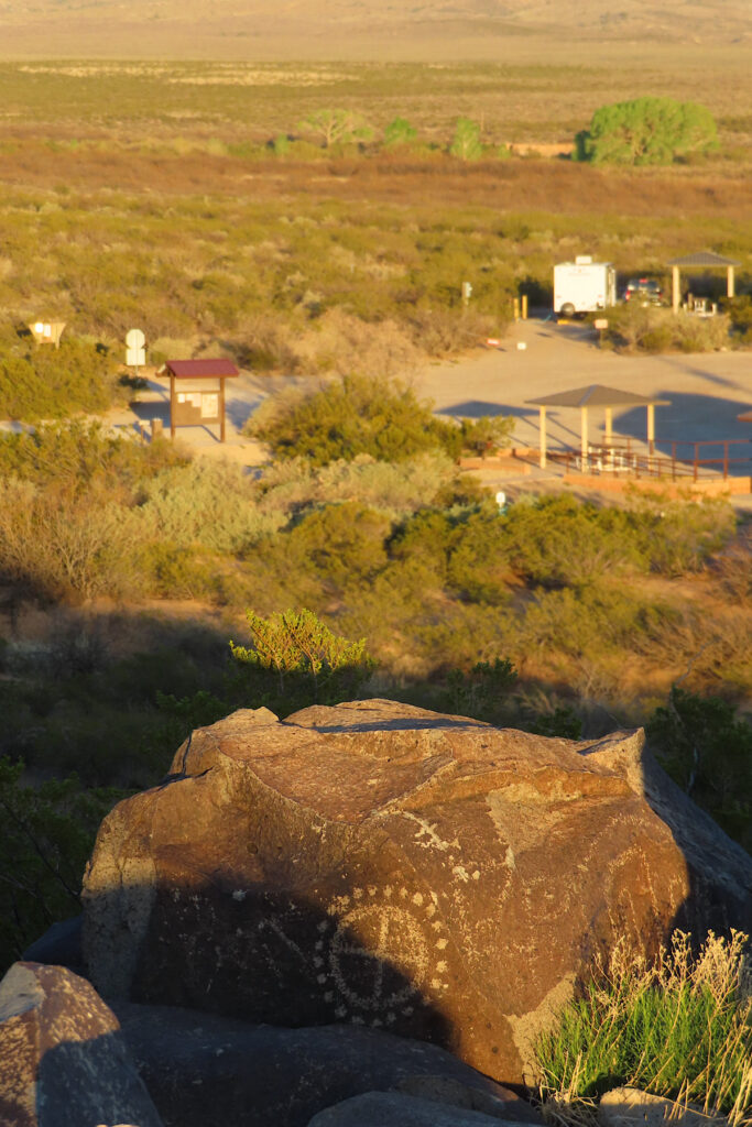 Rock etched with art above distant campground.