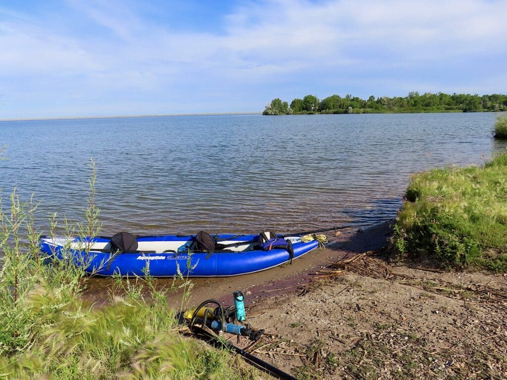 Blue inflatable kayak on lake shore.